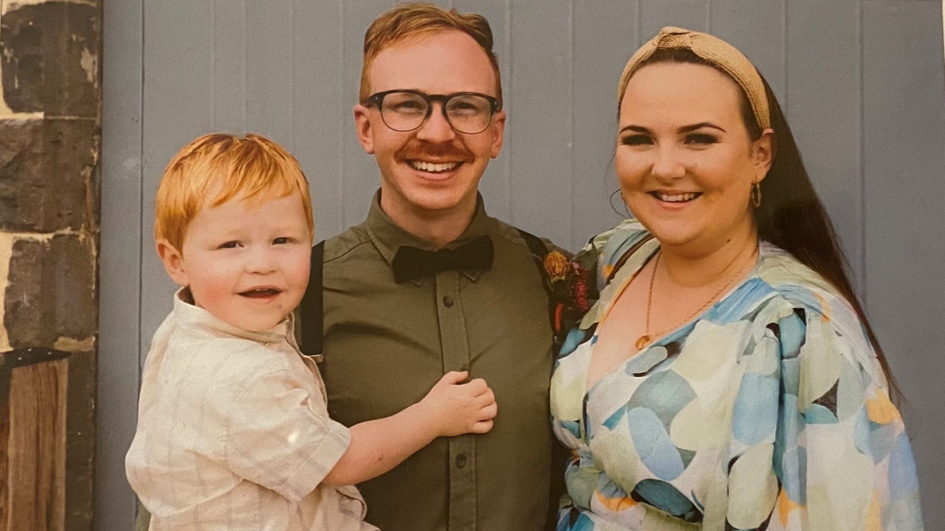Larson, a young boy with red hair and an adorable smile, is being held by his parents